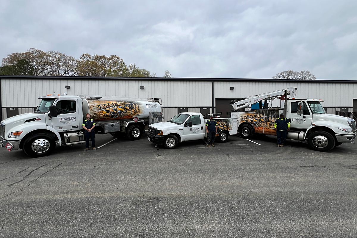 Three Henderson trucks parked in front of a building, showcasing their varied colors and sizes against the urban backdrop.