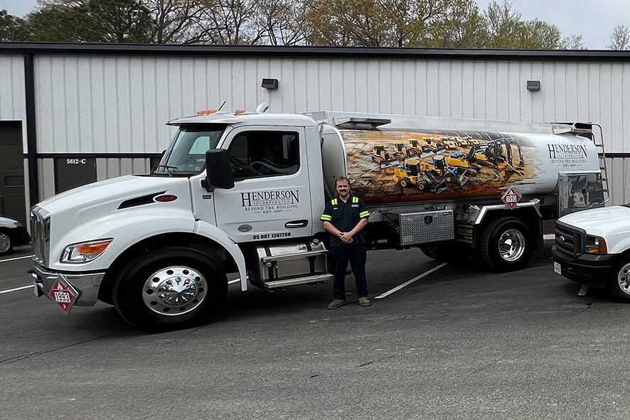 Three Henderson trucks parked in front of a building, showcasing their varied colors and sizes against the urban backdrop.